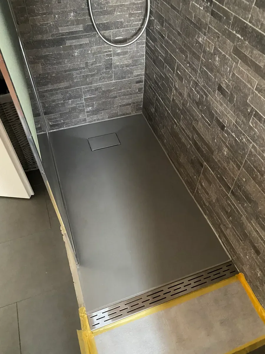 Fertige Dusche mit Steinwand und Bodenablauf