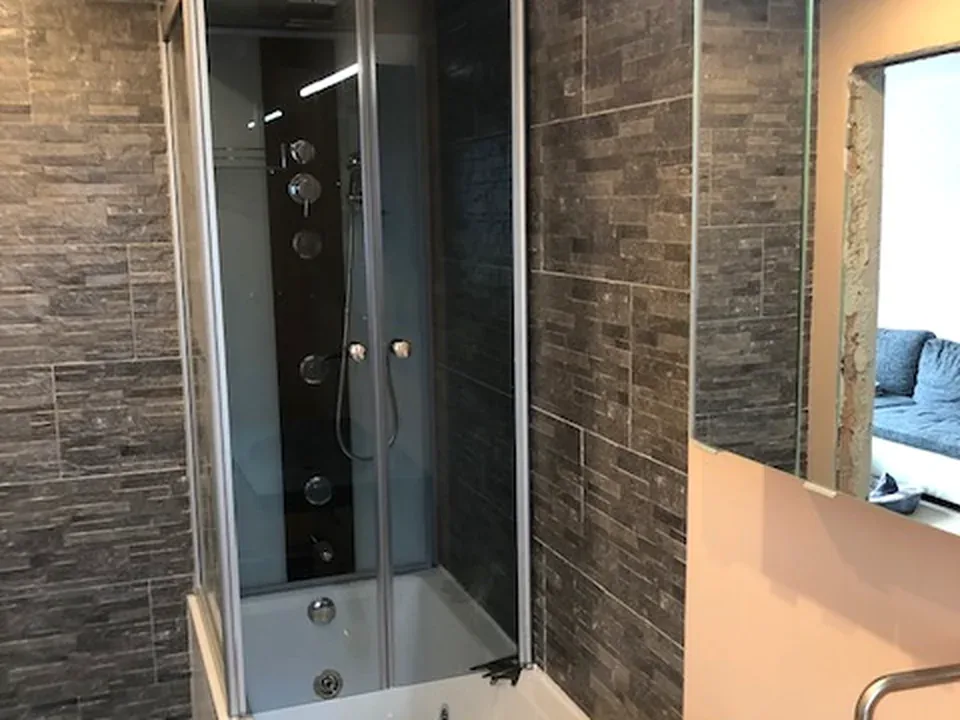 Fertiggestellte Dusche mit Steinwand im Badezimmer